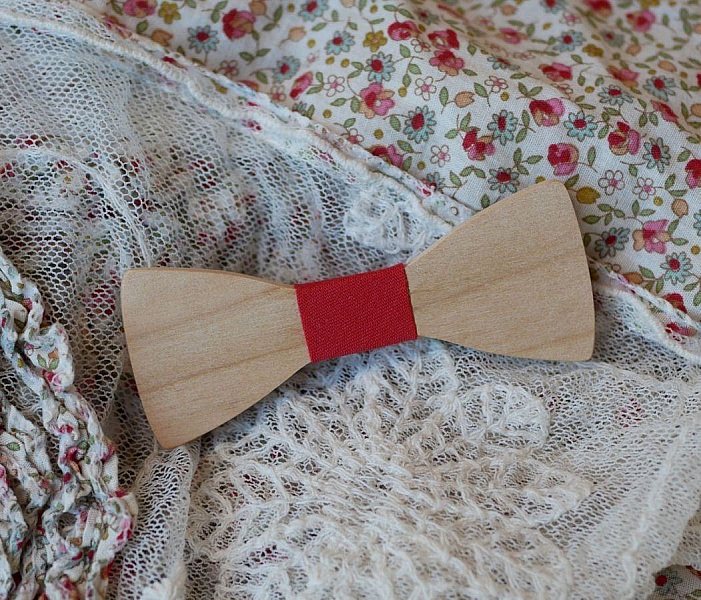 Nœud papillon en bois avec centre rouge sur tissu floral.